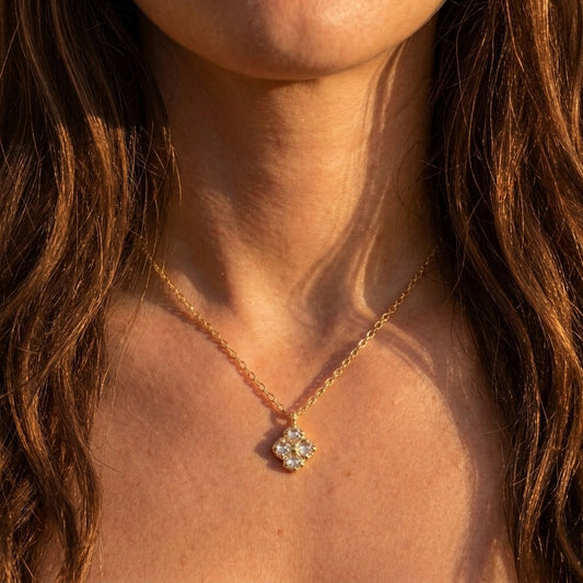 Close-up of a person wearing a gold necklace with a diamond pendant.