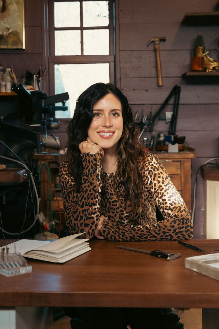 Woman sitting at a desk in a workshop with tools and equipment around