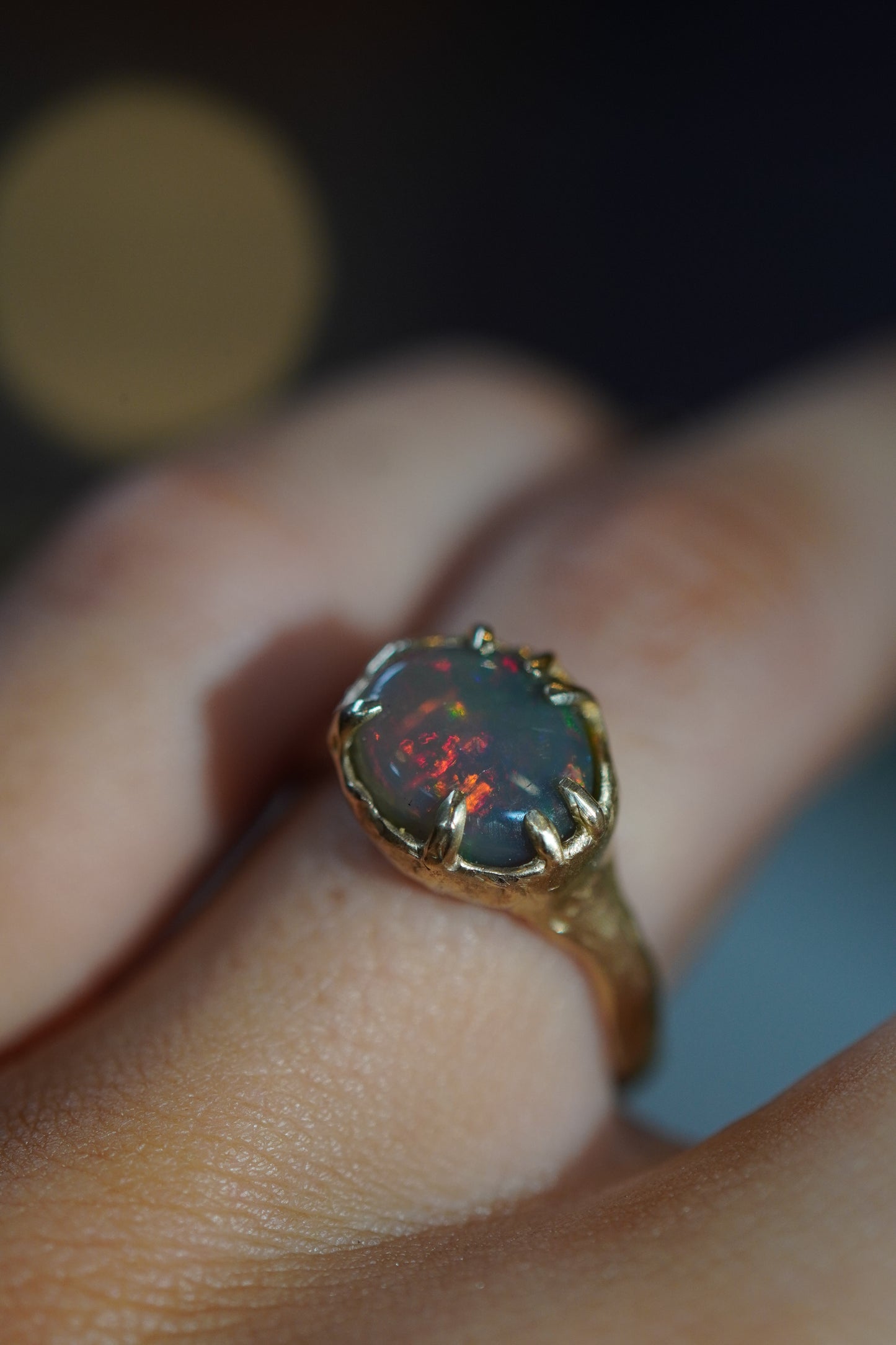 Opal ring on a finger with a blurred background