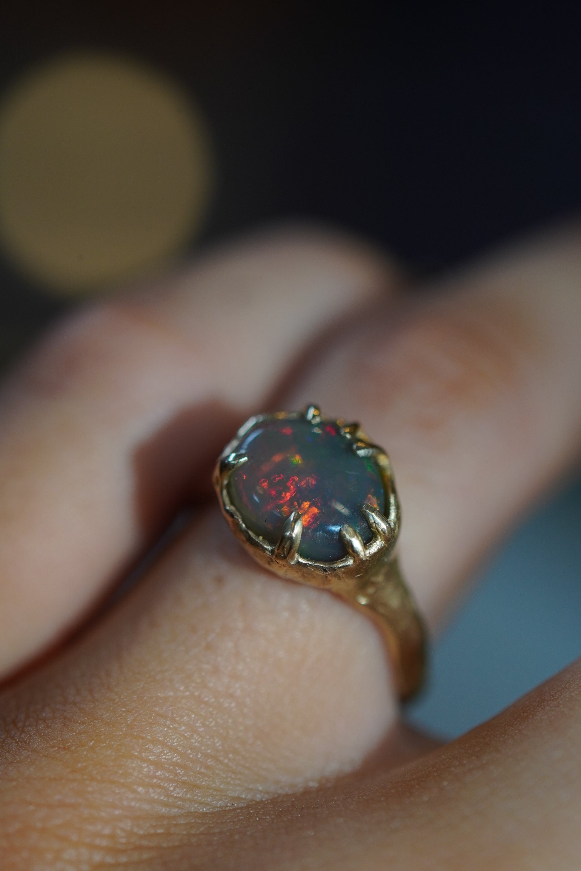 Opal ring on a finger with a blurred background