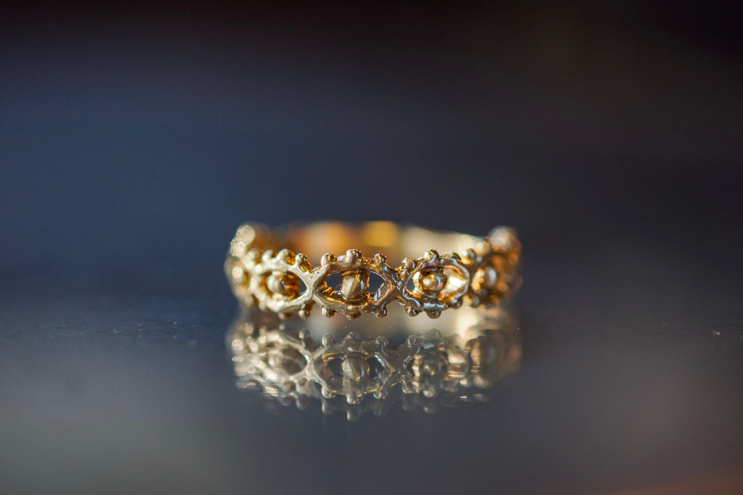 Gold ring with organic eye design on a reflective surface