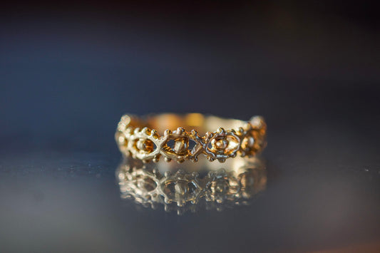 Gold ring with organic eye design on a reflective surface