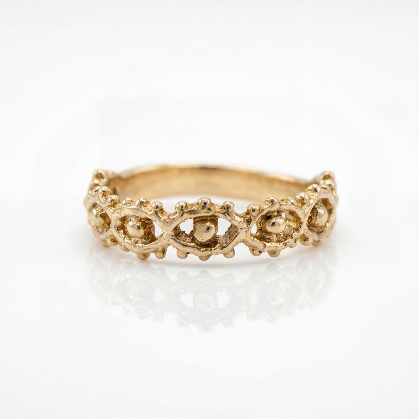 Gold ring with intricate eye design on a white background
