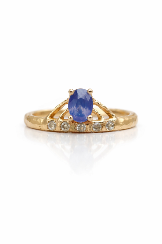 Gold ring with a blue sapphire and smaller sapphires on a white background